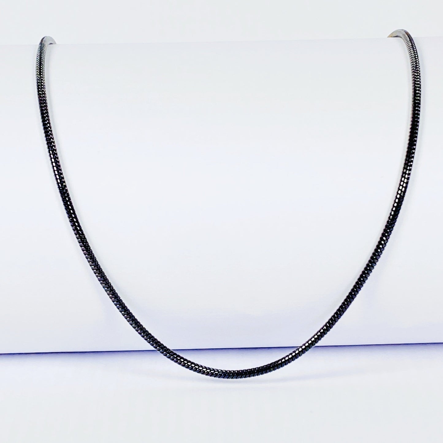 Black snake chain necklace on a light gray background