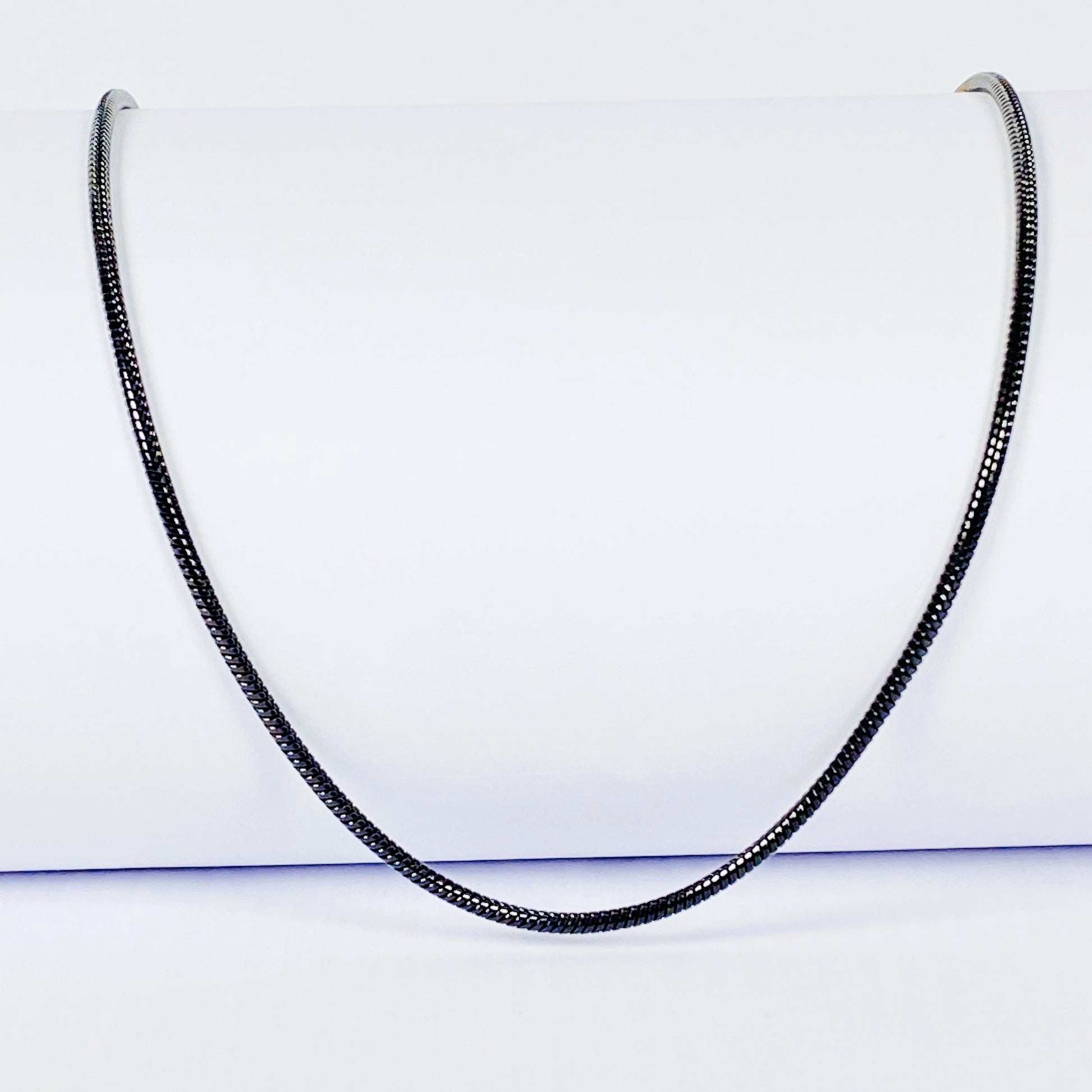 Black snake chain necklace on a light gray background