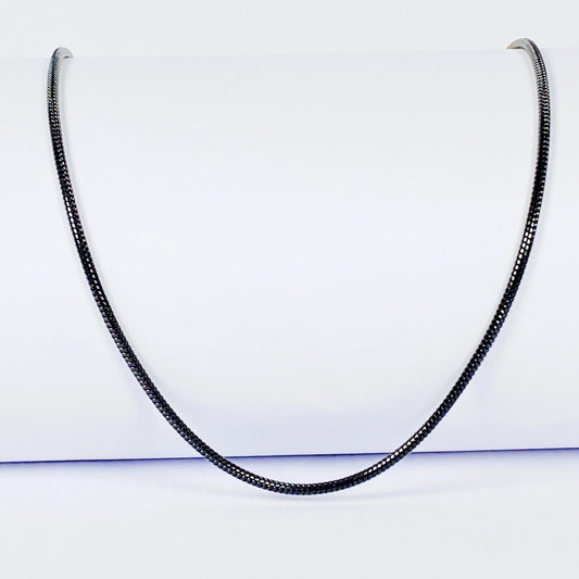Black snake chain necklace on a light gray background