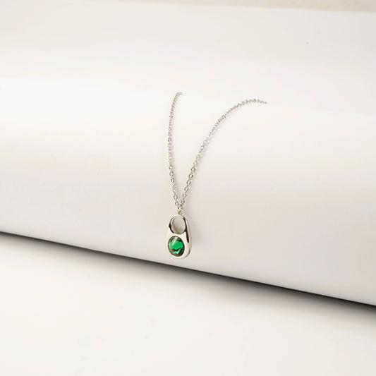 Silver necklace with a green gemstone pendant on a white surface