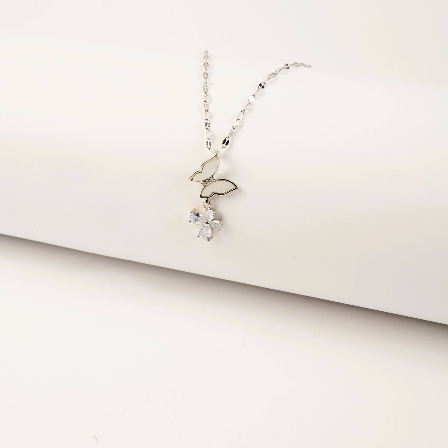 Delicate silver necklace with a small pendant on a light beige background